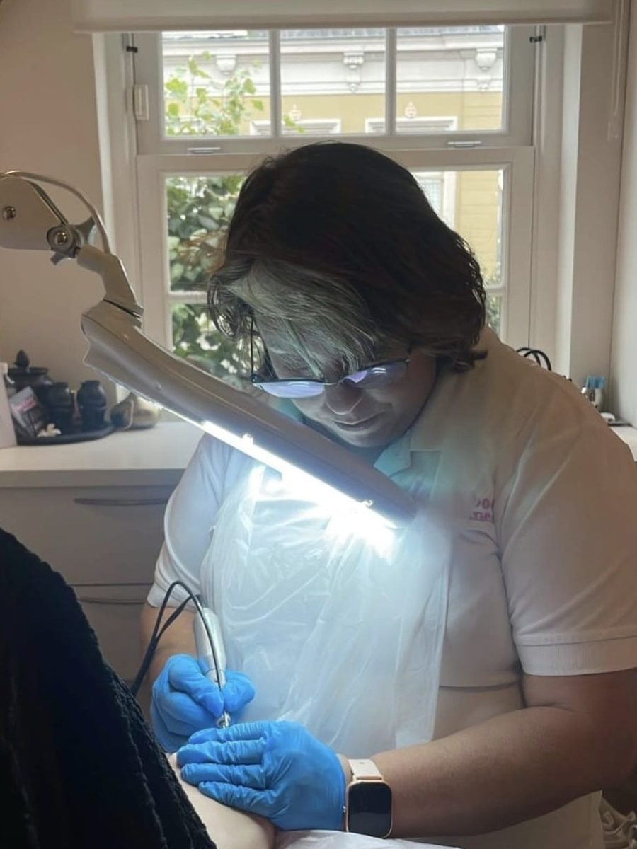 Monique, medisch pedicure, aan het werk in haar behandelkamer aan de Ramen 36 in Hoorn: met handschoenen en onder een lamp behandelt ze een voet